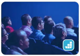 a diverse audience engrossed in a theater presentation, captivated by the speakers on stage